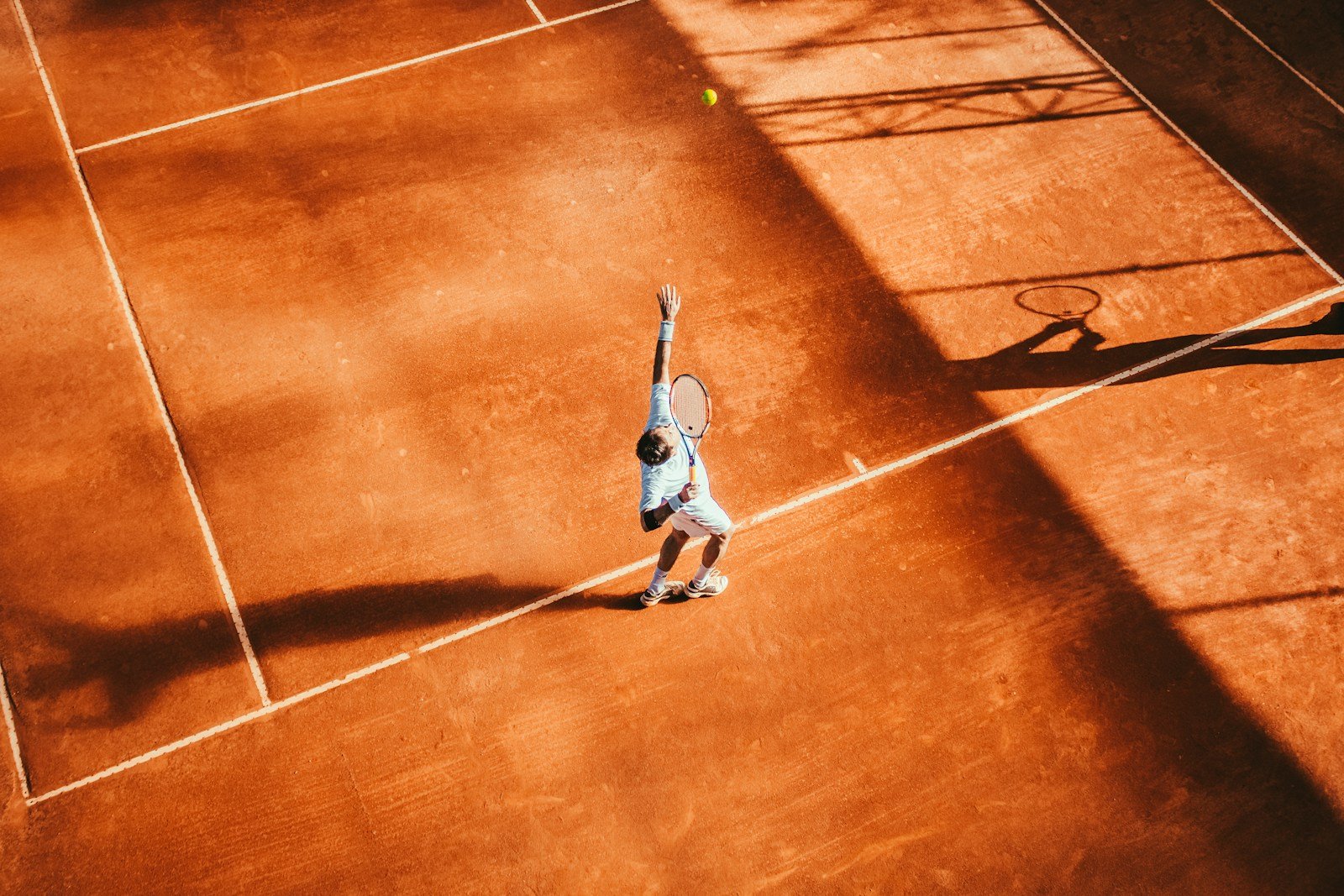 Tennis player serving on a clay court
